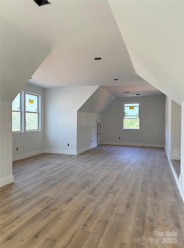 bonus room with baseboards, vaulted ceiling, and light wood finished floors