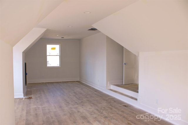 bonus room with visible vents, light wood-type flooring, baseboards, and vaulted ceiling