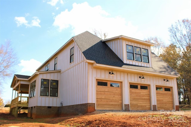 view of side of home with a shingled roof, a garage, board and batten siding, and crawl space