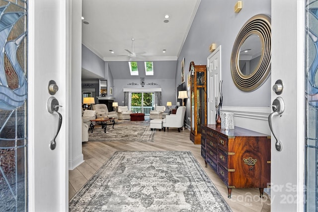 interior space featuring crown molding, ceiling fan, vaulted ceiling, and light hardwood / wood-style floors