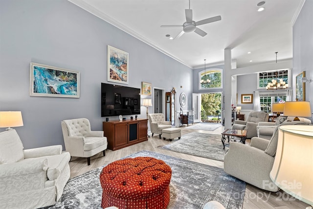 living room with ceiling fan with notable chandelier, a high ceiling, ornamental molding, and light hardwood / wood-style flooring