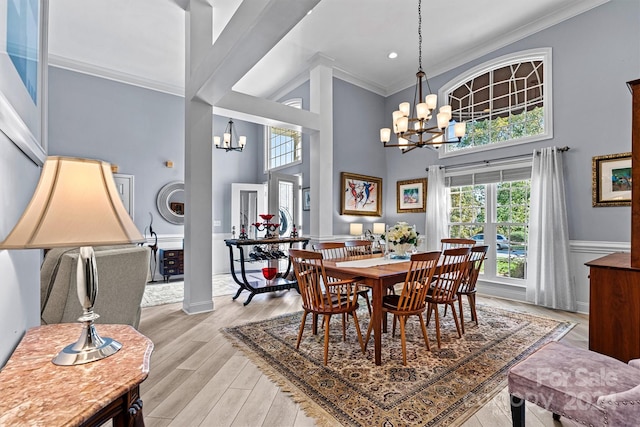 dining area with light wood finished floors, a high ceiling, an inviting chandelier, and ornamental molding