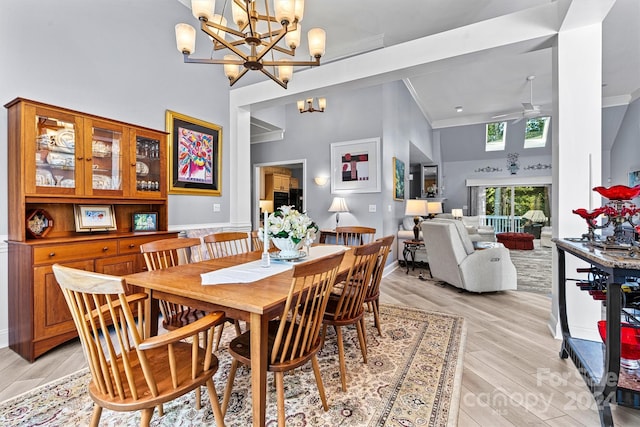 dining area with ceiling fan with notable chandelier, light hardwood / wood-style flooring, a towering ceiling, and ornamental molding