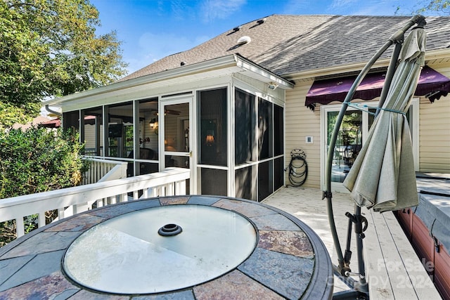 rear view of house featuring a sunroom, outdoor dining area, roof with shingles, and a deck