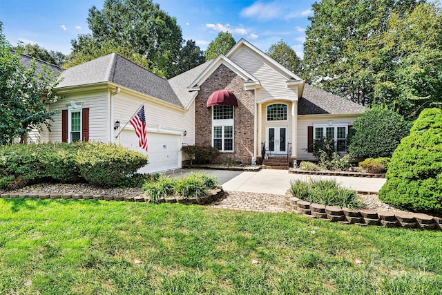 view of front facade featuring driveway, french doors, a front yard, a garage, and brick siding