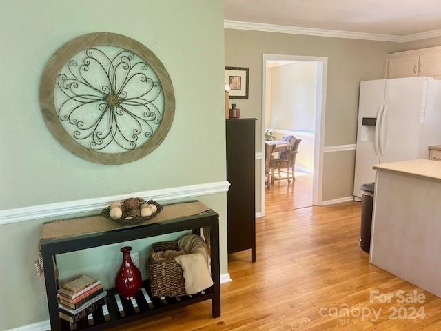 hall with light hardwood / wood-style flooring and ornamental molding