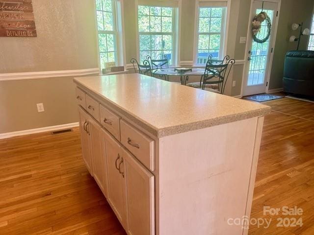 kitchen featuring visible vents, a center island, light wood-type flooring, baseboards, and white cabinetry