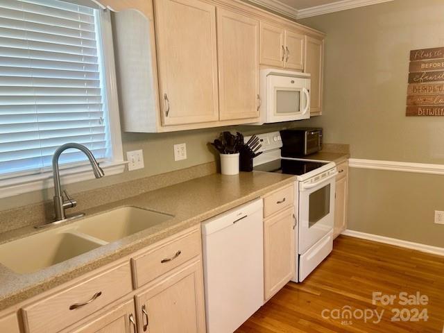 kitchen with hardwood / wood-style floors, crown molding, white appliances, and sink