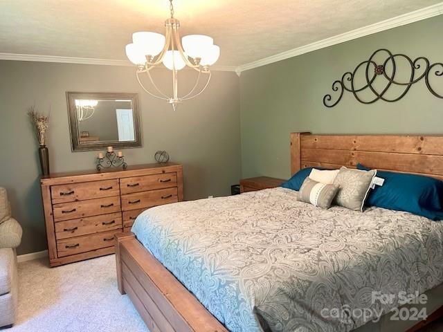 carpeted bedroom with crown molding and an inviting chandelier