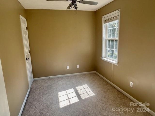 empty room featuring a healthy amount of sunlight, ceiling fan, and carpet