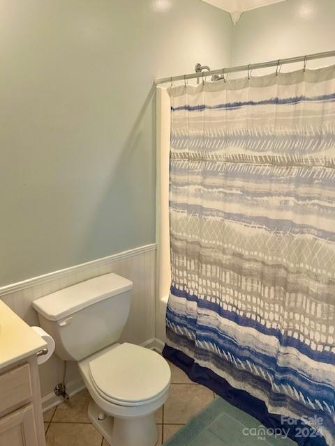 bathroom with curtained shower, tile patterned floors, a wainscoted wall, vanity, and toilet