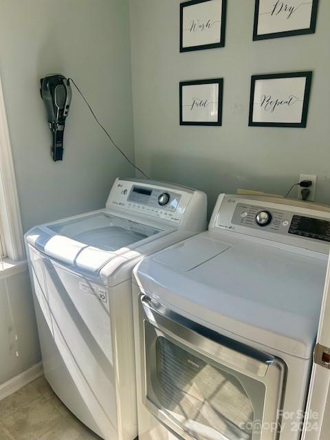 clothes washing area with baseboards, laundry area, and washing machine and clothes dryer