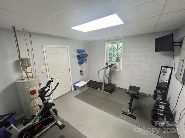 workout room with water heater and a paneled ceiling