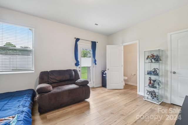 bedroom with multiple windows, connected bathroom, and light wood-type flooring