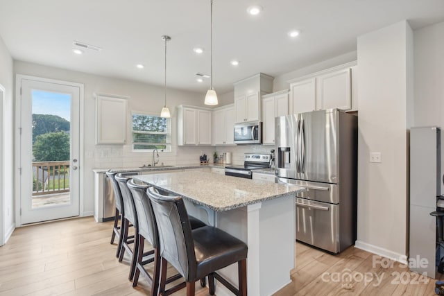 kitchen featuring sink, a kitchen island, white cabinetry, appliances with stainless steel finishes, and decorative backsplash