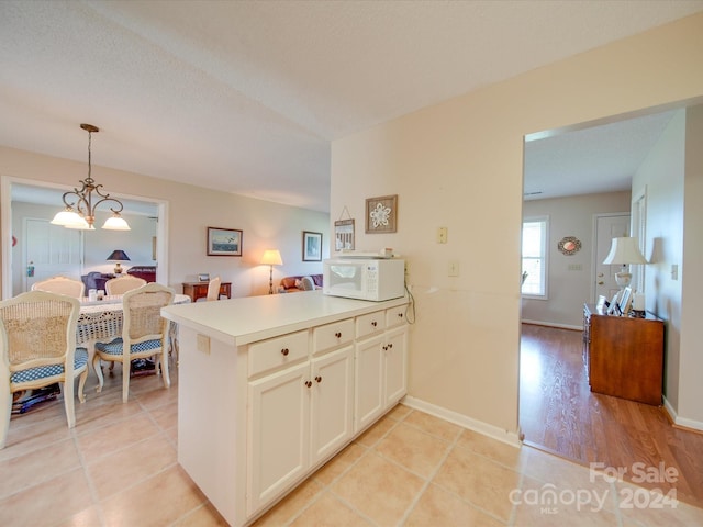 8510 Olive Branch Rd, Marshville, NC 28103 - kitchen featuring white microwave, a peninsula, pendant lighting, light countertops, and white cabinetry