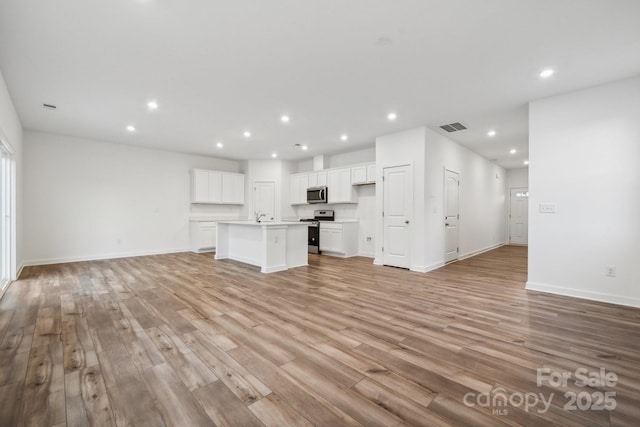 unfurnished living room featuring light wood-type flooring and sink