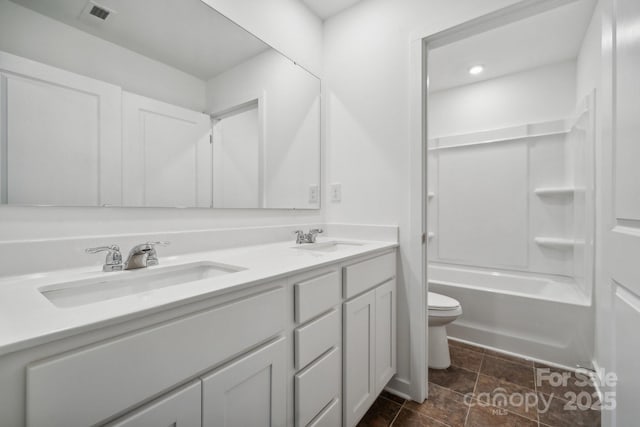 full bathroom featuring washtub / shower combination, vanity, and toilet