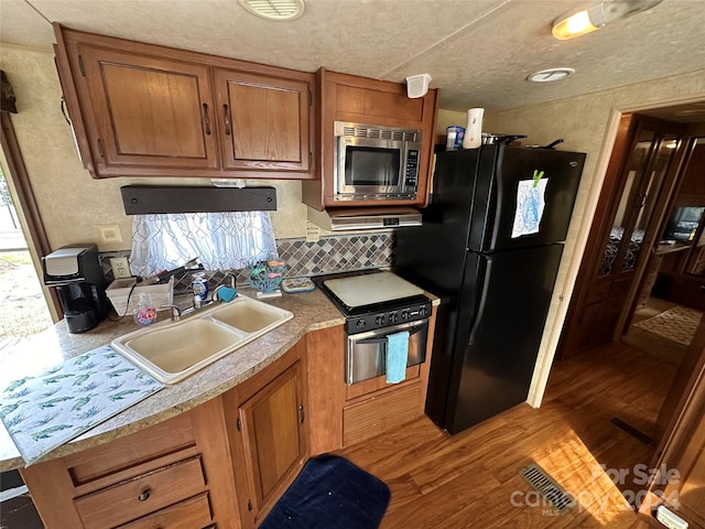 kitchen with backsplash, wood-type flooring, stainless steel appliances, sink, and a textured ceiling