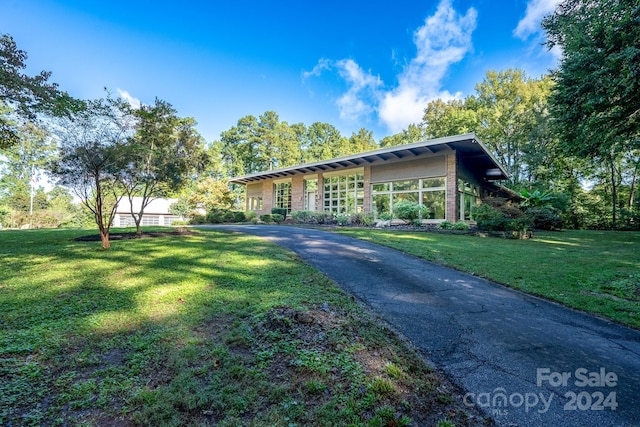mid-century inspired home featuring aphalt driveway and a front lawn