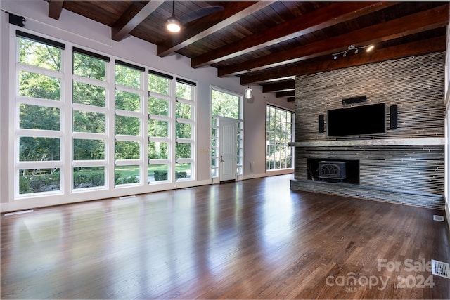 unfurnished living room with a wood stove, beam ceiling, wooden ceiling, and dark hardwood / wood-style flooring