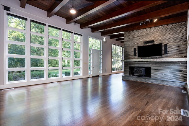 unfurnished living room with wooden ceiling, beamed ceiling, a large fireplace, and wood finished floors