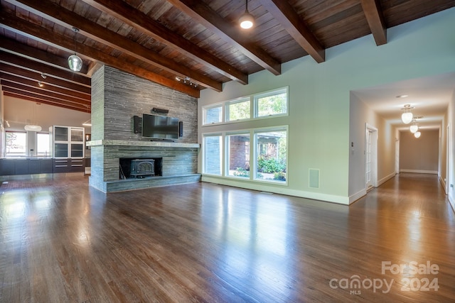 unfurnished living room with beamed ceiling, baseboards, wooden ceiling, a fireplace, and wood finished floors