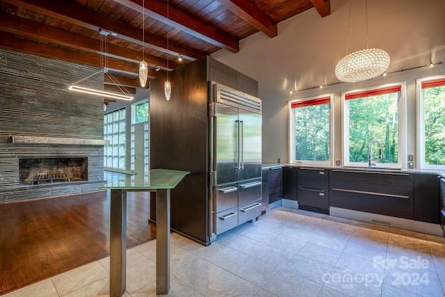 kitchen featuring light tile patterned floors, stainless steel built in refrigerator, beamed ceiling, wooden ceiling, and modern cabinets