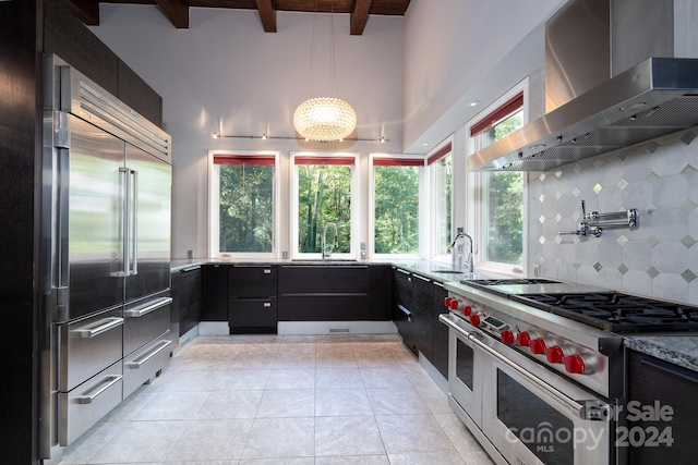 kitchen with modern cabinets, beam ceiling, wall chimney exhaust hood, high end appliances, and backsplash