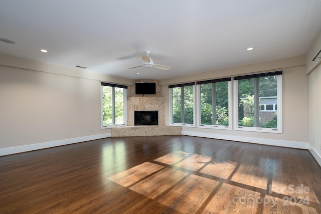unfurnished living room featuring ceiling fan, baseboards, a wealth of natural light, and a fireplace