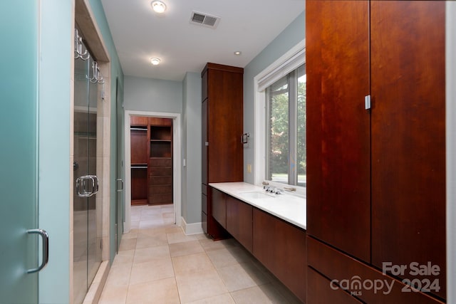 full bathroom featuring baseboards, tile patterned floors, a shower stall, a walk in closet, and visible vents