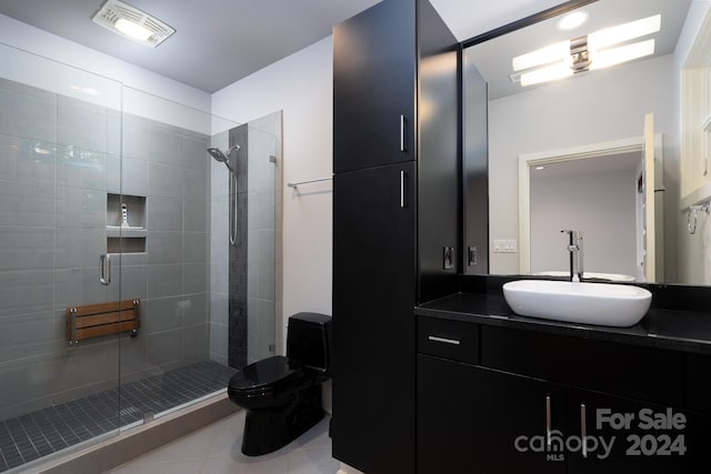 bathroom with tile patterned floors, a shower with door, vanity, and toilet