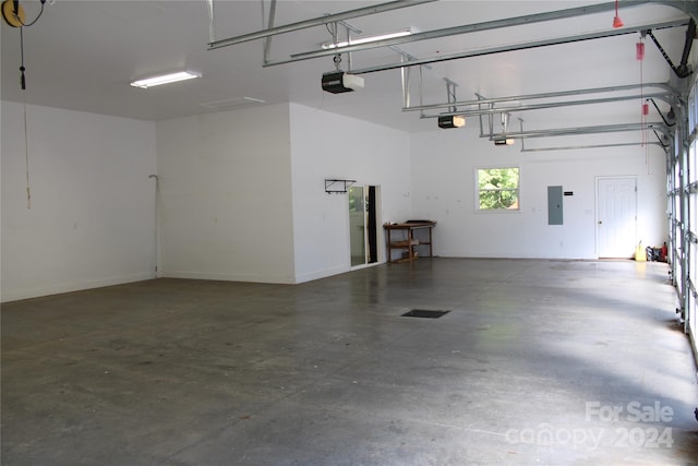 garage featuring electric panel, a garage door opener, and baseboards