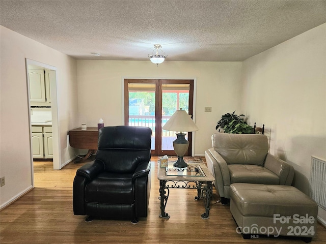 living area featuring a textured ceiling and hardwood / wood-style flooring