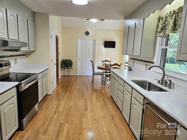 kitchen featuring sink, gray cabinetry, a textured ceiling, appliances with stainless steel finishes, and light hardwood / wood-style floors