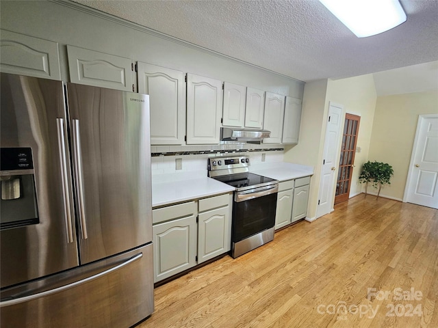 kitchen featuring light hardwood / wood-style flooring, stainless steel appliances, a textured ceiling, and tasteful backsplash