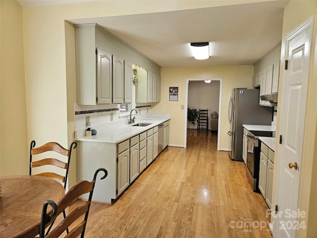 kitchen featuring sink, a textured ceiling, ventilation hood, stainless steel appliances, and light wood-type flooring