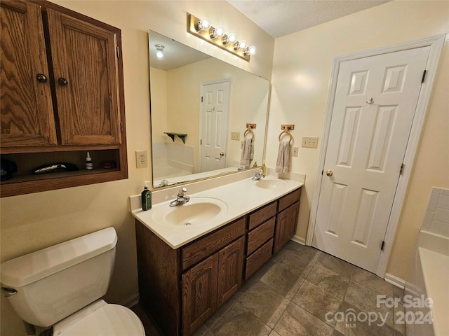 bathroom featuring vanity, a textured ceiling, toilet, and a washtub