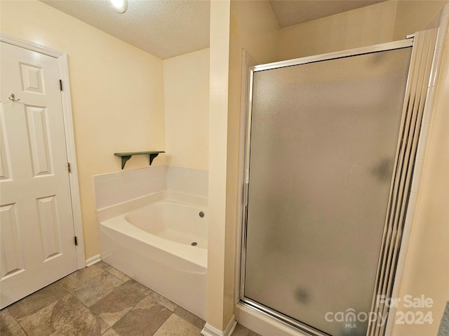 bathroom featuring a textured ceiling and separate shower and tub