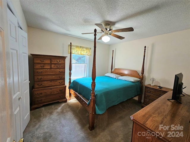 bedroom with ceiling fan, a textured ceiling, a closet, and dark colored carpet