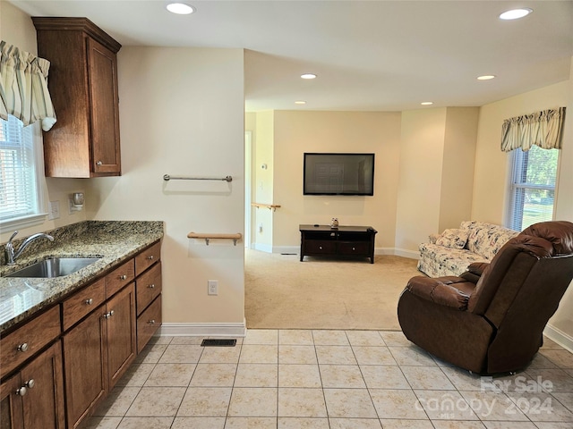 kitchen with dark stone countertops, light tile patterned floors, and sink