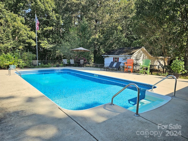 view of pool with a patio and an outbuilding