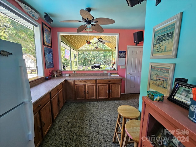 kitchen with ceiling fan, white refrigerator, and dark colored carpet