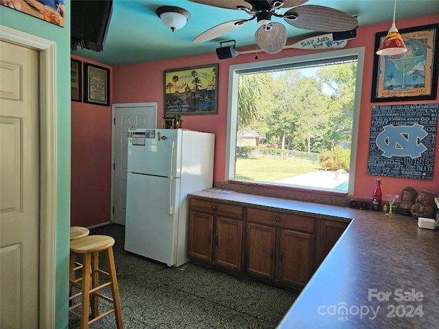 kitchen featuring decorative light fixtures, ceiling fan, and white fridge