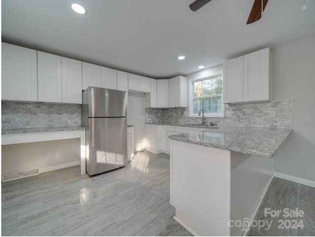 kitchen with ceiling fan, backsplash, stainless steel fridge, and white cabinetry