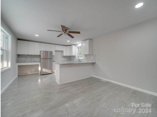 kitchen with white cabinets, stainless steel refrigerator, sink, and kitchen peninsula