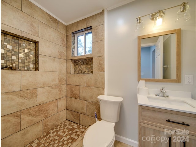 bathroom featuring ornamental molding, vanity, tiled shower, and toilet