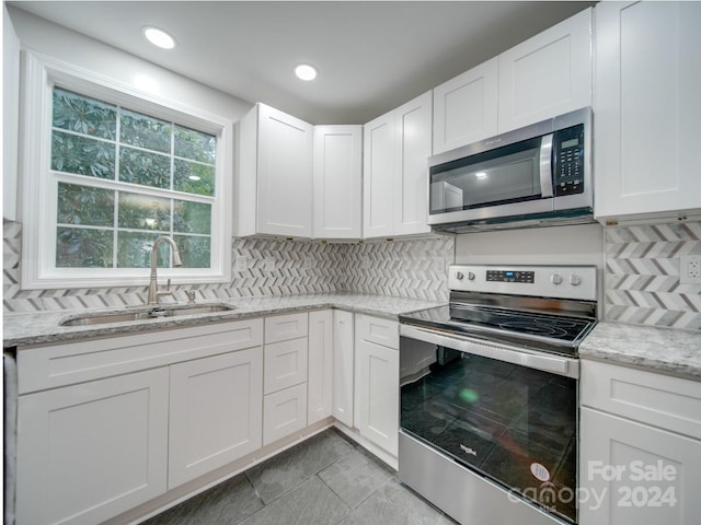 kitchen featuring light stone counters, sink, white cabinetry, appliances with stainless steel finishes, and decorative backsplash