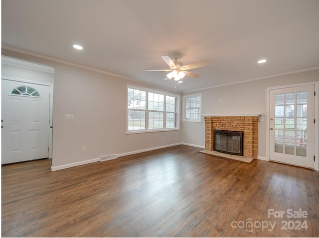 unfurnished living room with a fireplace, crown molding, dark wood-type flooring, and ceiling fan