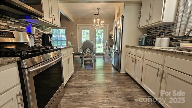 kitchen with light stone countertops, stainless steel appliances, a chandelier, pendant lighting, and decorative backsplash